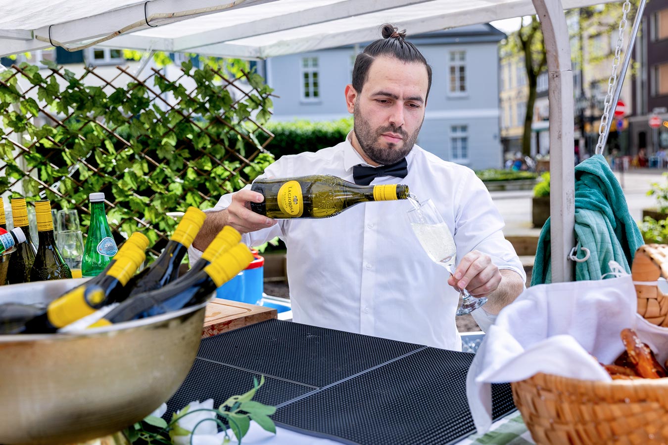 Ein mobiler Barmann schenkt nach der Trauung auf dem Kirchplatz Sekt in Gläser