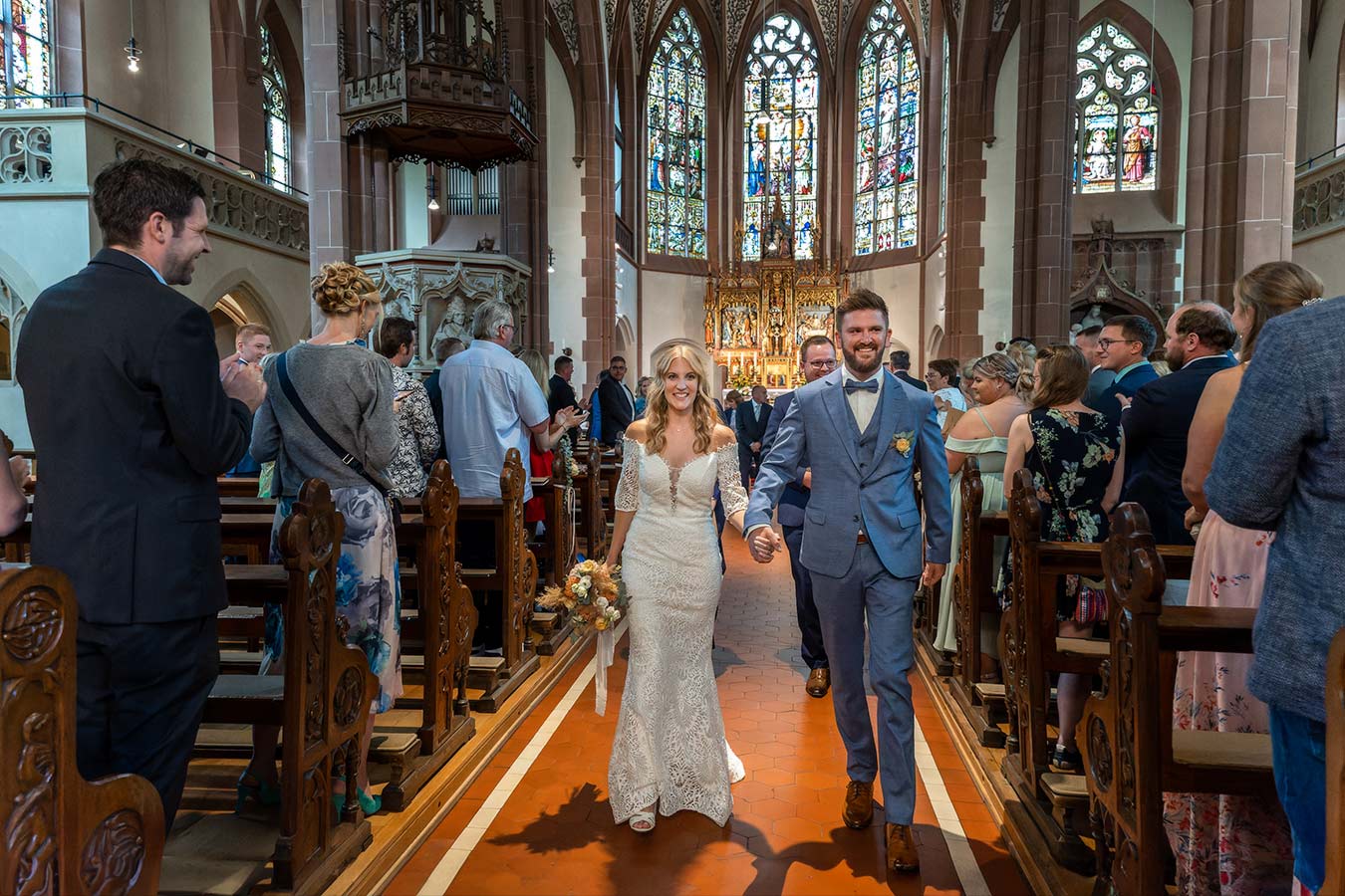 Das Brautpaar zieht gemeinsam an den Gästen vorbei aus der Kirche St. Lambert in Ense